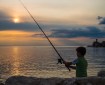 A young boy fishing in the setting sun at Piran Slovenia